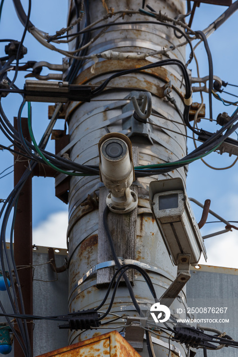 two old cctv security surveillance cameras on street light pole on blue sky background