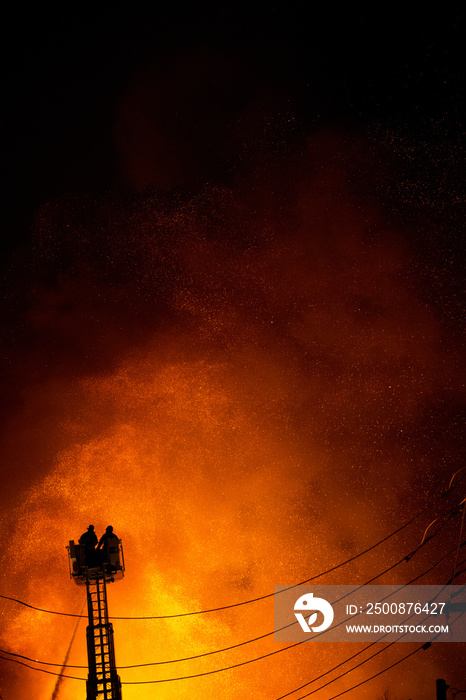 Firefighters on ladder putting out building fire