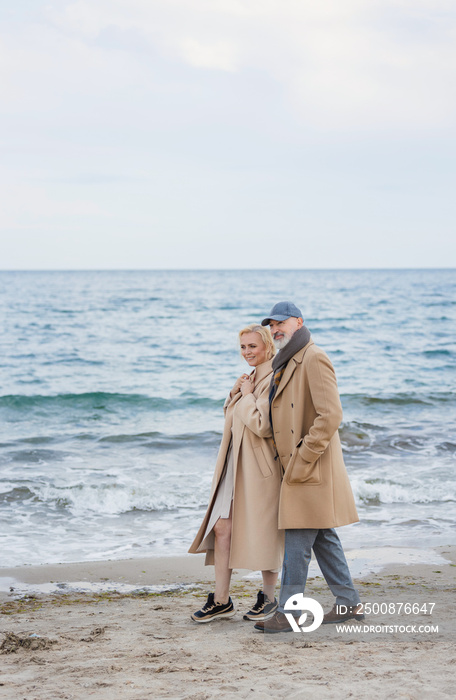 Aged couple walking along the beach against the background of the sea