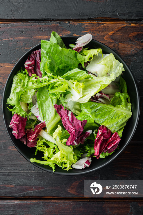 Fresh leaves of different lettuce salad, on old dark  wooden table background, top view flat lay