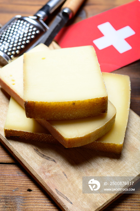 Assortment of Swiss cheeses Emmental or Emmentaler medium-hard cheese with round holes, Gruyere, appenzeller and raclette used for traditional cheese fondue and gratin and flag of Switzerland