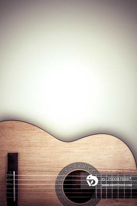 Part of an acoustic guitar on a grey background.