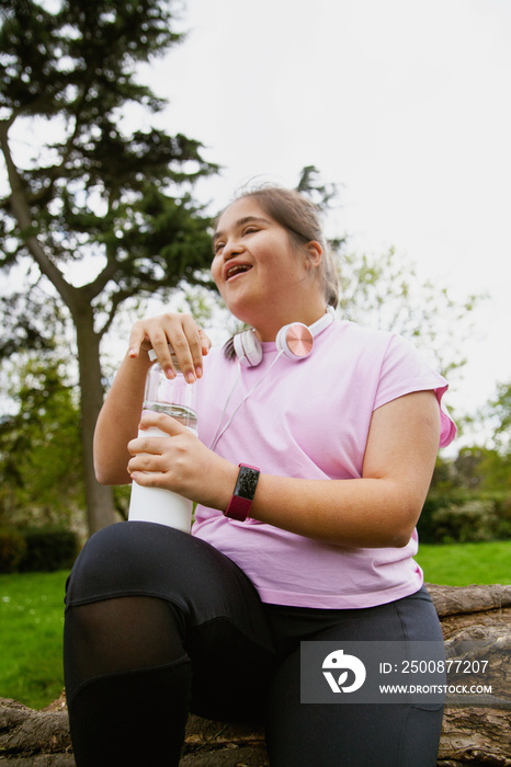 Young curvy girl with Down Syndrome holding reusable water bottle after workout