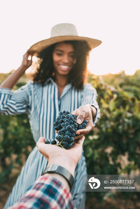 Hands sharing a bunch of grapes with a happy blurred woman