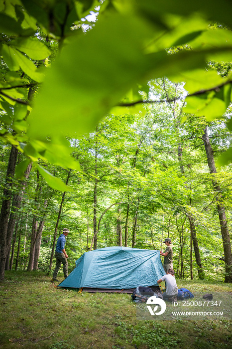 Air Force service member sets up a tent with his sons on  a backpacking trip.