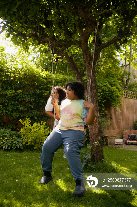 Plus-sized boy sitting on a swing in the garden