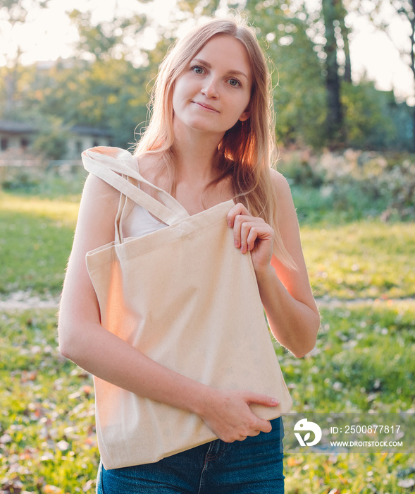 Woman holding canvas tote bag on nature background. Eco friendly concept. Outdoors