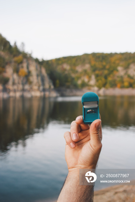 Man holding a blue box with engagement ring front beautiful landscape. An offer of marriage in Zvikov Castle, Czech Republic. Film effect, author processing of photo