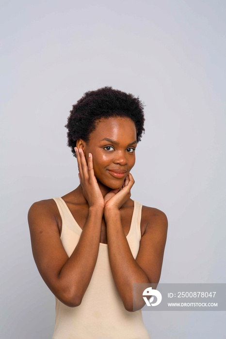 Studio portrait of smiling woman in cream colored tank top