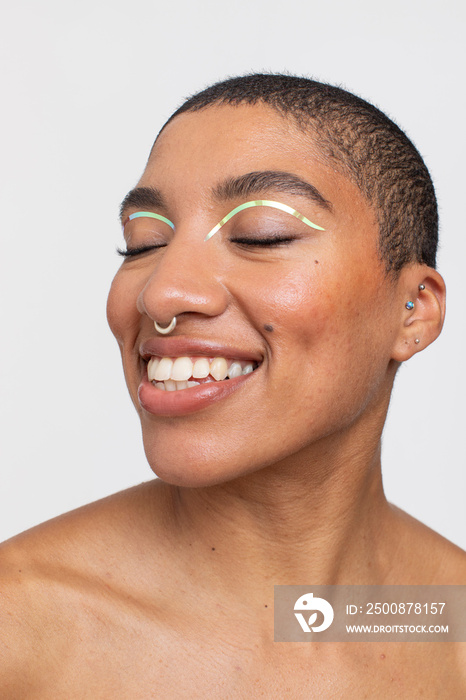 Studio portrait of smiling woman with golden foil make-up