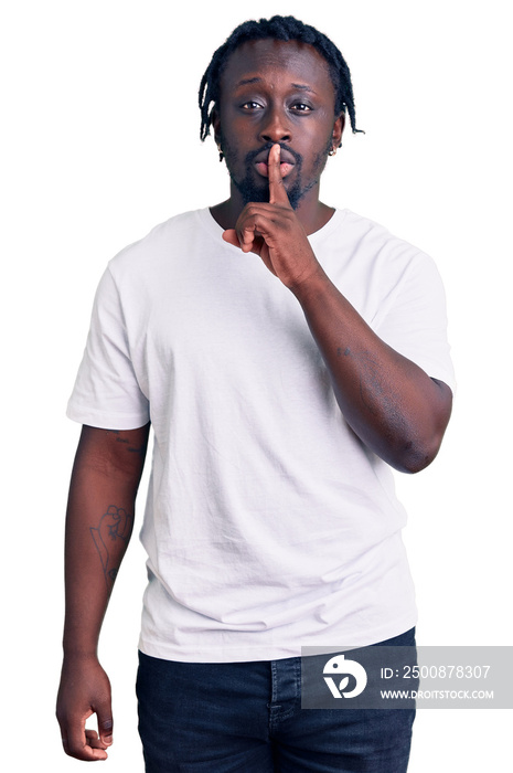 Young african american man with braids wearing casual white tshirt asking to be quiet with finger on lips. silence and secret concept.