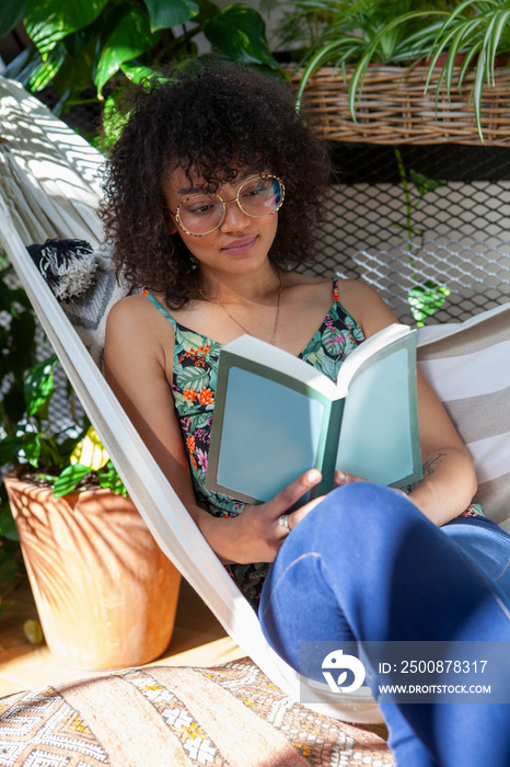 Woman sitting in hammock and reading book