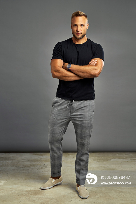 Handsome man posing with watch and looking at camera, isolated on gray background