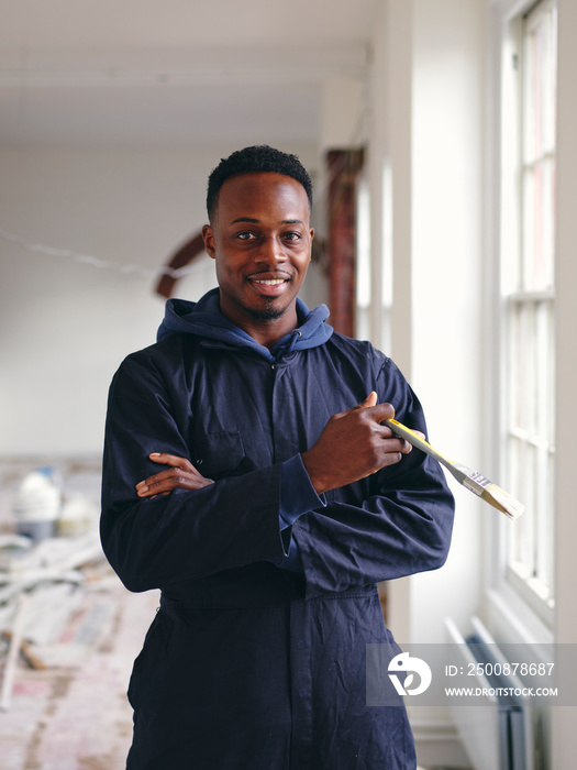 Portrait of smiling man holding paintbrush during renovation