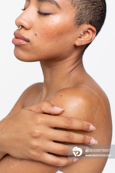 Studio shot of shirtless woman with arms crossed and eyes closed