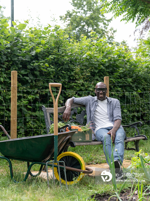 Smiling mature man resting on bench after working in garden