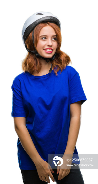 Young beautiful woman wearing cyclist helmet over isolated background looking away to side with smile on face, natural expression. Laughing confident.