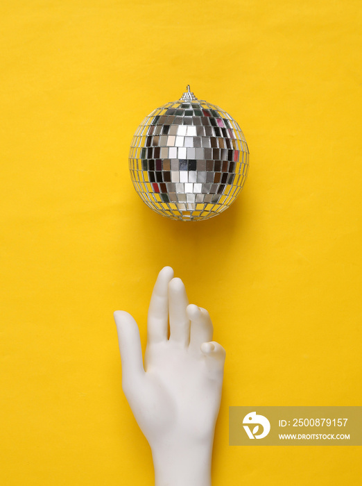 Disco ball and hand on yellow background. Minimalism party concept