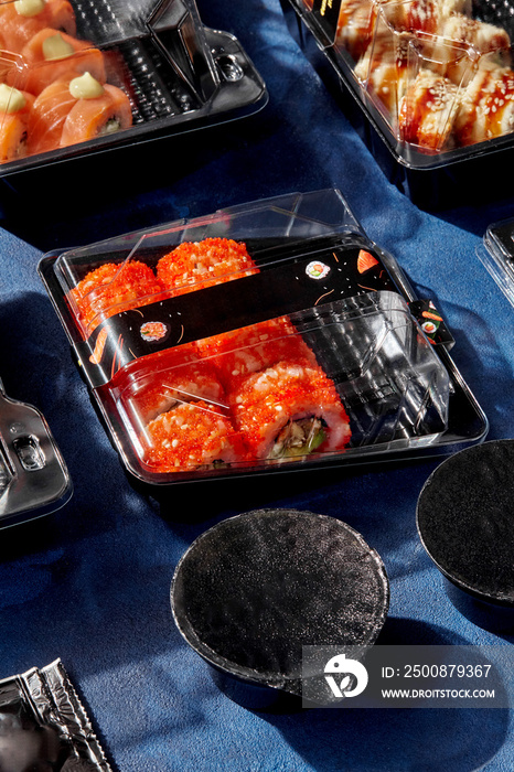 Set of sushi rolls packed in closed plastic containers for delivery to client