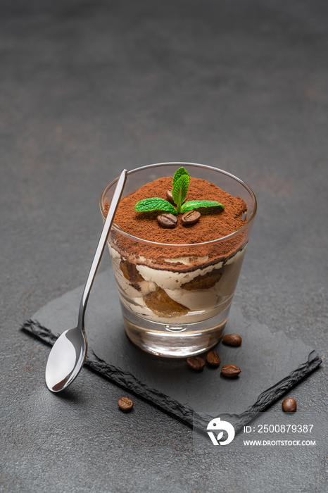 Classic tiramisu dessert in a glass on stone serving board on dark concrete background