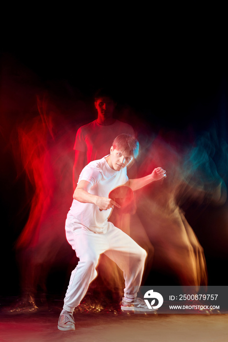 young man playing table tennis in mixed neon light