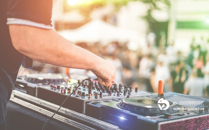 Dj mixing outdoor at beach party festival with crowd of people in background - Summer life, view of disco club outside - Soft focus on hand - Fun ,youth,entertainment and fest concept