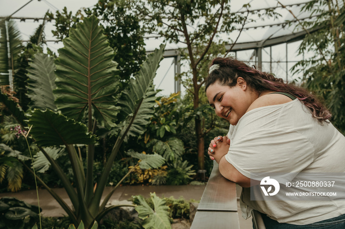 plus size woman leans on railing and looks at pond