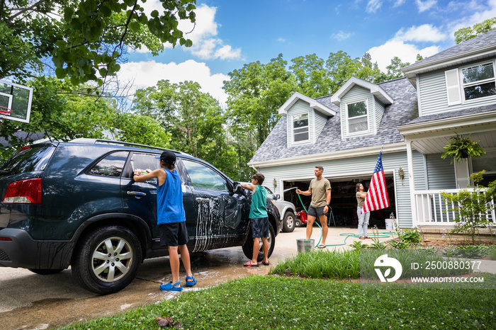 Air Force service member washes his vehicles with his sons in the driveway.