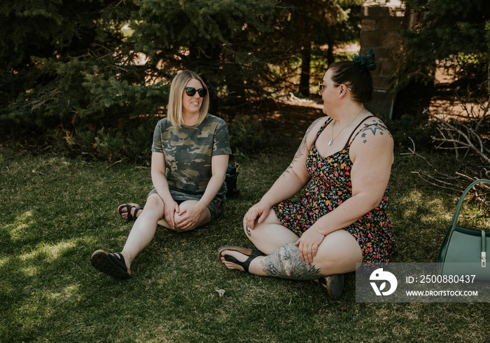 2 women sit and talk in the park