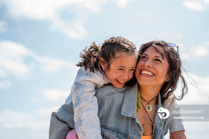 Smiling mother giving daughter (8-9) piggyback ride