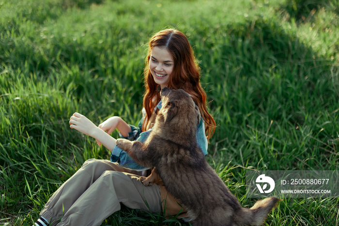 Woman lying on the grass smiling playing and cuddling her dog in nature in the park in the summer sunset. The concept of health and love of animals, treatment of ticks and fleas grass and animals