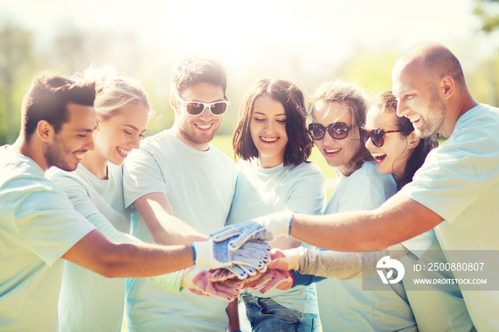 group of volunteers putting hands on top in park