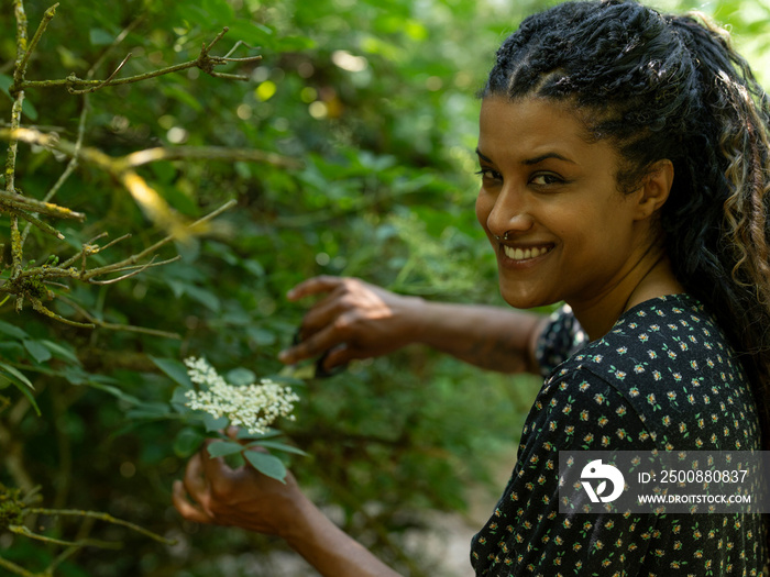 Portrait of woman cutting branch of tree