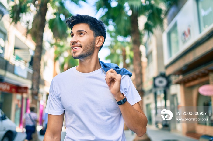 Young latin man smiling happy walking at the city.