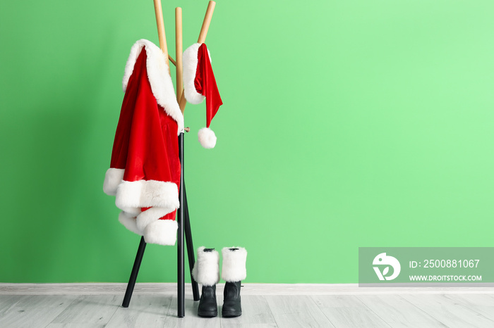 Hanger with Santa Claus costume and boots near color wall