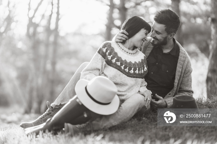 Black and white photos. Lovely hipster couple with bike . Couple wearing beautiful hats and sweaters. Lifestyle, happy couple of two play on a sunny day in the park.  Sunset in autumn.