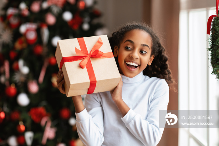 Happy Black Girl Shaking Christmas Present At Home