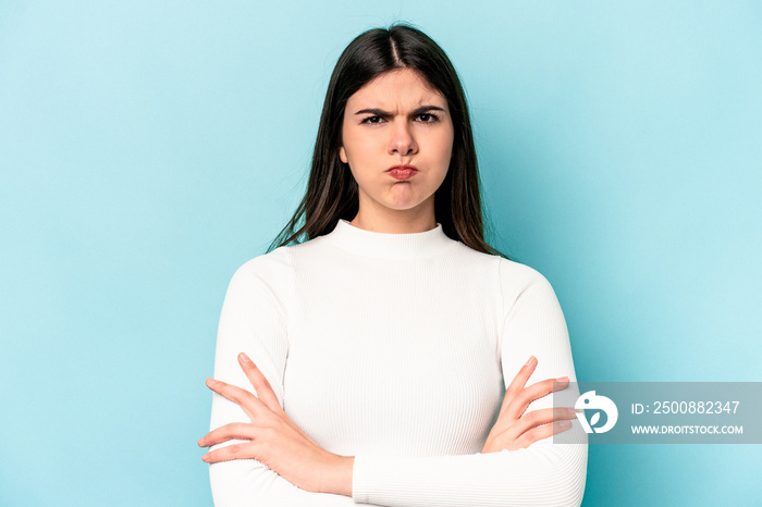 Young caucasian woman isolated on blue background blows cheeks, has tired expression. Facial expression concept.