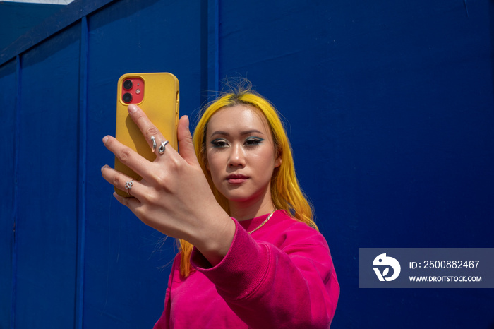 Young woman with yellow hair taking selfie outdoors