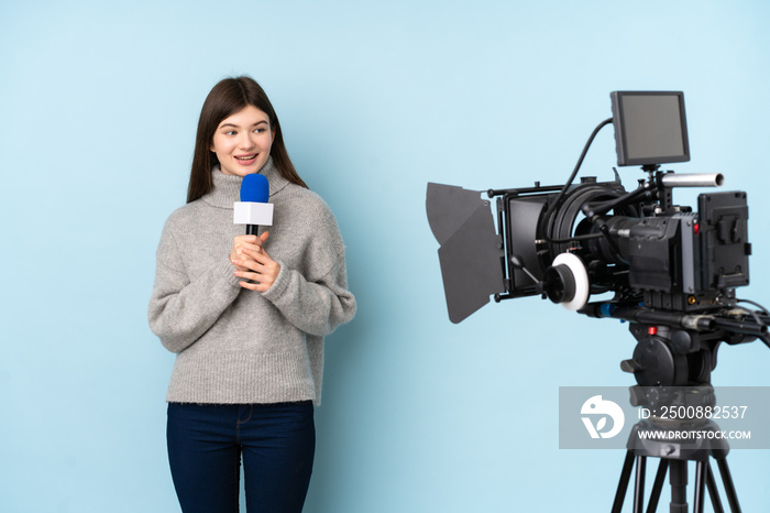 Reporter woman holding a microphone and reporting news over isolated blue background