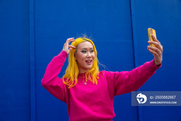 Young woman with yellow hair taking selfie outdoors