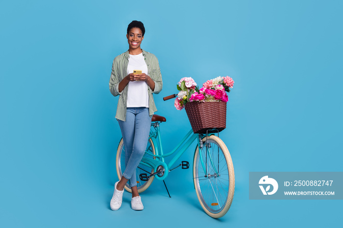 Full length portrait of nice person stand near bike use gadget isolated on blue color background