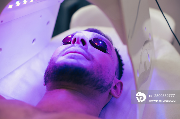 Young man smiling in solarium while getting suntan