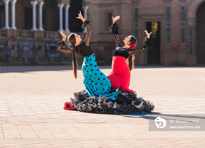 Two women dressed in flamenco costume doing a choreography in a square