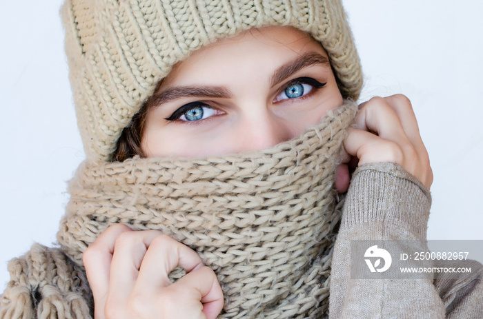 Close-up portrait of a woman in a scarf and hat with beautiful blue eyes