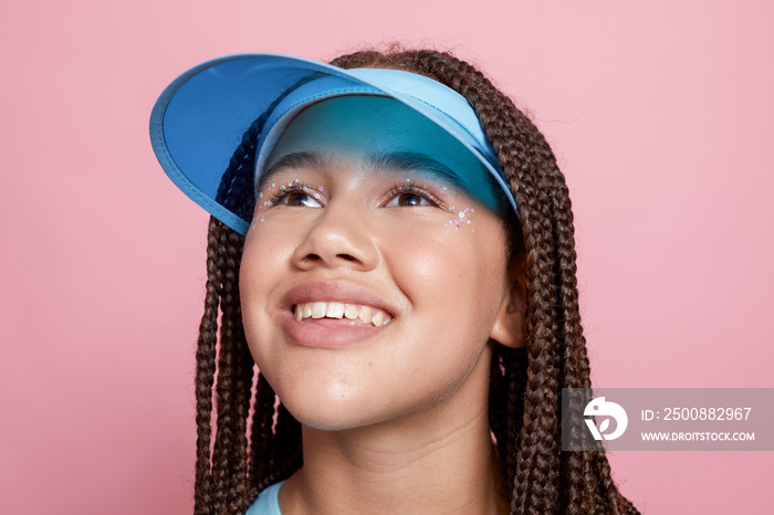 Studio portrait of smiling girl wearing sun visor