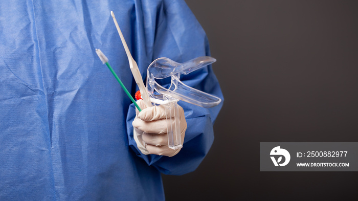 A female doctor is a gynecologist in a blue robe. Gynecological accessories, venus mirror, brush. Grey background, empty space for text.