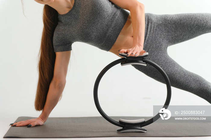 Fit young brunette pilates instructor showing different exercises on a white background a mat.