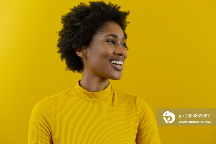 Cheerful young african american businesswoman with afro hairstyle looking away against yellow wall