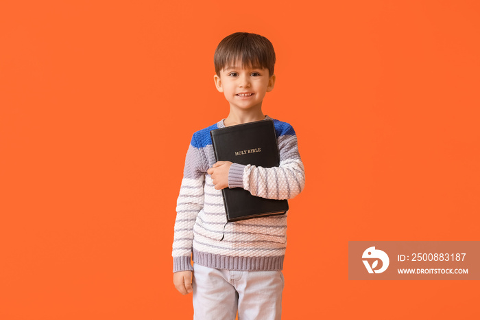 Little boy with Bible on color background